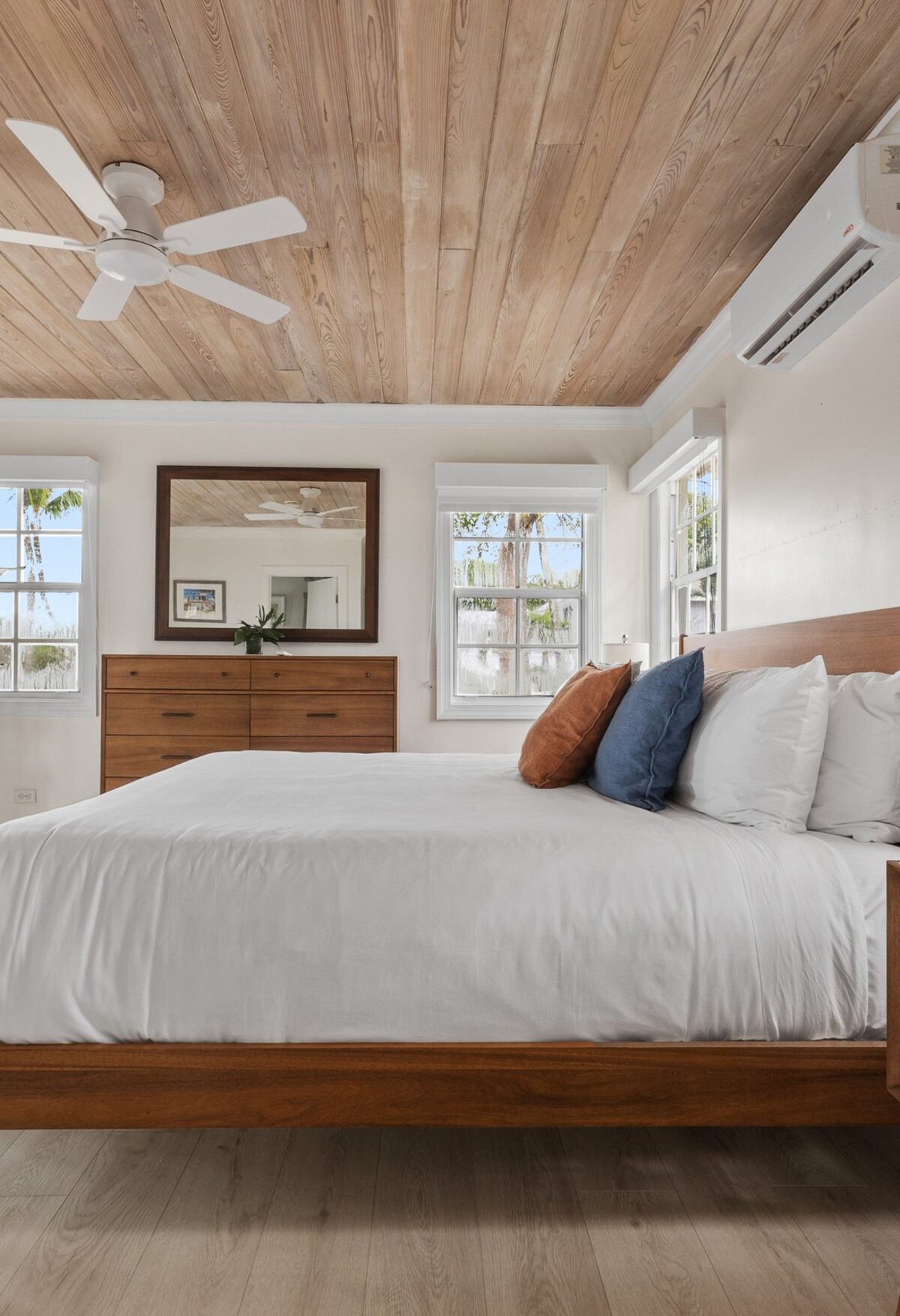 A guest room at Romora Bay with a wooden ceiling and white bedding